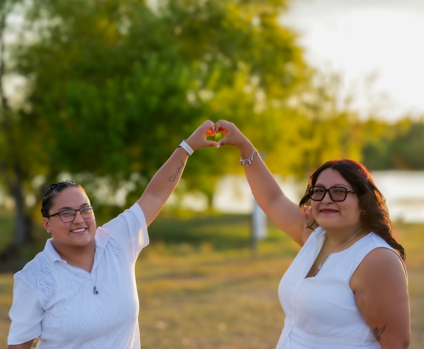 Engaged couple forming a heart with their hands in golden-hour light