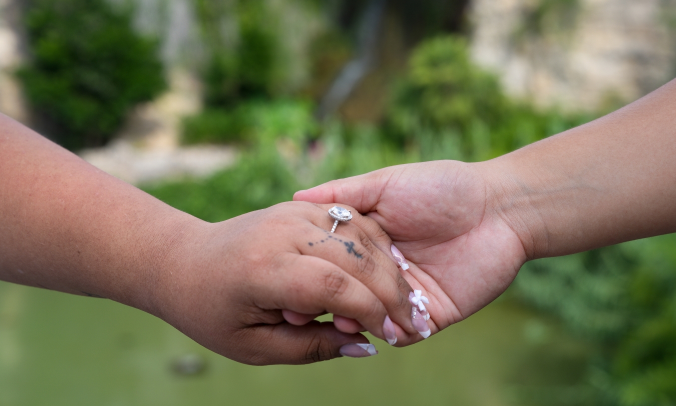 Close-up of an engaged couple holding hands and showing the ring