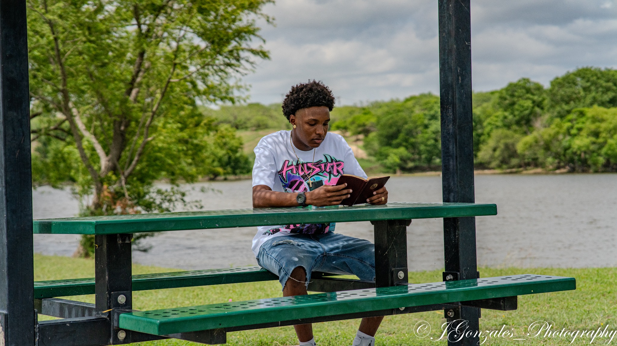 Graduate seated at a picnic table near the water