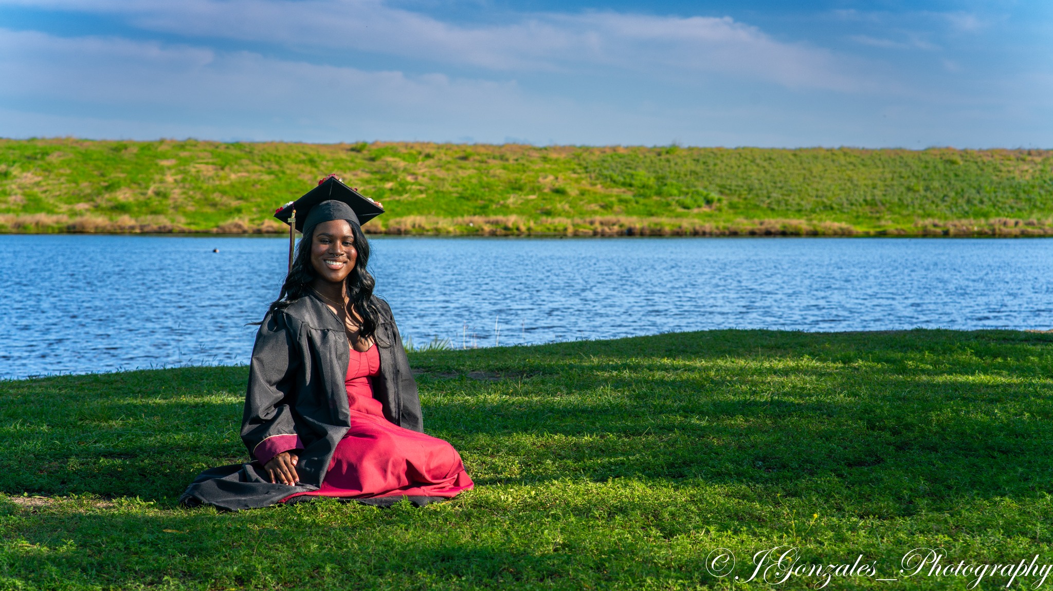 Graduate in cap and gown beside the water
