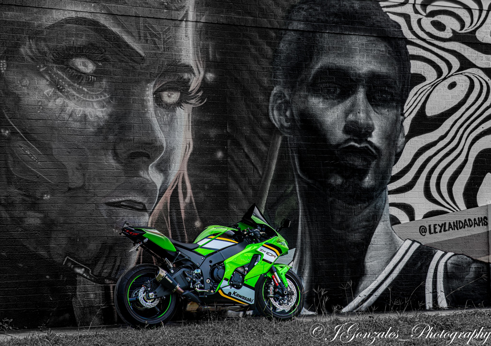 Green sport motorcycle photographed in front of a large mural